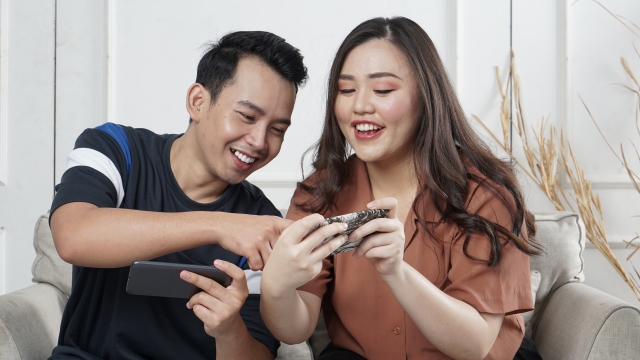 a young couple watching videos together on their phones and smiling